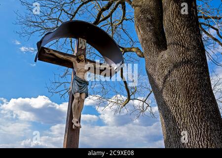 Häufiger Anblick in Bayern, Jesus am Kreuz, geschnitzte Skulptur am Wegesrand Stockfoto