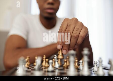 Konzentrierter junger schwarzer Mann, der Schach spielt, wenn er während der Quarantäne zu Hause bleibt Stockfoto