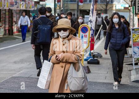 Tokio, Japan. Februar 2020. Menschen, die Gesichtsmasken als vorbeugende Maßnahme tragen, gehen inmitten der Coronavirus-Krise auf der Straße.der zweimonatige Ausnahmezustand, der von der japanischen Regierung als Reaktion auf die COVID-19-Pandemie ausgerufen wurde, endete am 1. Juni. Obwohl Japan die hohen Infektionen und Sterblichkeitsraten einiger Länder während der ersten Krisenwelle vermieden zu haben scheint, wurden in vielen Gebieten in Tokio und im ganzen Land Geschäfte geschlossen und geschlossen. Die Annullierung der Olympischen Spiele 2020 in Tokio und die zunehmende Zahl von Infektionen, da die Menschen wieder zu einem normaleren Leben zurückgingen Stockfoto