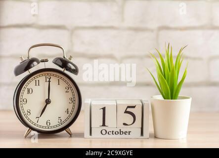 15. Oktober auf einer hölzernen Kalender neben der Wecker, das Datum der Herbst Monat. Stockfoto