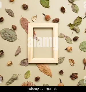 Hölzerner Fotorahmen mit herbstlichen trockenen Blättern auf khaki braunem Hintergrund. Flach liegend, Draufsicht, Kopierraum Stockfoto