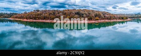 Breites schönes Panorama von Bäumen am Seeufer mit malerischen Wolken Reflexionen im Wasser wachsen Stockfoto