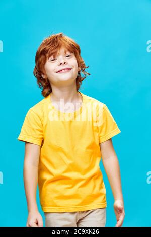 Sommersprossen rothaariges Kind in gelbem T-Shirt lächelnd auf blauem Hintergrund Stockfoto