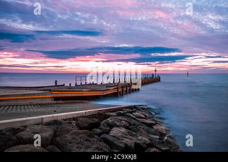 Landschaftlich schöner Sonnenuntergang über Meer und Bootssteg - Landschaft mit langer Belichtung Stockfoto