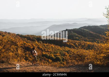 Schwangere Frau nordic Walking mit Trekkingstöcken auf Hügel mit schöner Herbstbergsicht. Schwangerschaft Aktivität und gesunde Lebensweise in der Mutterschaft Zeit. Reisekonzept. Stockfoto