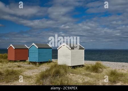 Farbenfrohe rot-blaue und weiße Strandhütten am Findhorn Beach, Moray Coast, Schottland Stockfoto