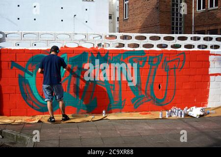 Straßenkünstler malt ein buntes Graffiti an einer weißen Wand Stockfoto