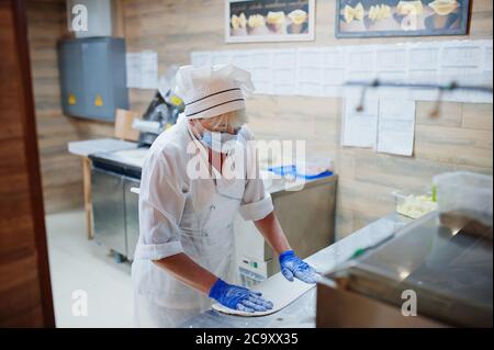 Pizzahersteller in Schutzmaske in der Pizzeria arbeiten. Stockfoto