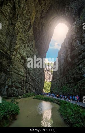 Wulong, China - August 2019 : Massen von Touristen zu Fuß auf einem schmalen Weg in Richtung der natürlichen felsigen Bogenspaltung in einer Schlucht unter Karstlandschaft Stockfoto