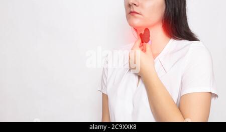 Das Mädchen hält ihren Hals mit einer Schilddrüse und ihre Hand auf weißem Hintergrund. Schilddrüsenerkrankungen und Probleme Konzept, Schmerzen und Behandlung, Jod Stockfoto