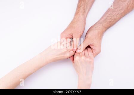 Die Hände der Frau in den Händen des Mannes liegen auf weißem Hintergrund. Mann und Frau halten Hände, Beziehung, Ehe, Vorschlag Stockfoto