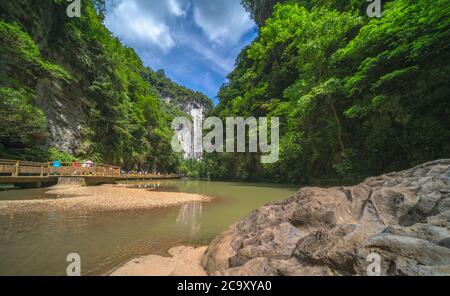 Wulong, China - August 2019 : Touristen auf einem hölzernen künstlichen Brückenweg entlang eines Flusses, der durch die Landschaft der massiven vertikalen fließt Stockfoto