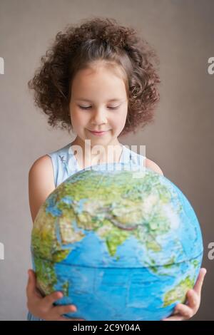 Kindertag. Ein schönes lockiges Mädchen hält den Planeten. Stockfoto