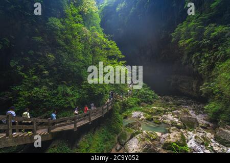 Wulong, China - August 2019 : Touristen, die auf einem künstlichen Holzweg entlang des Baches Fluss durch die Schlucht und das Land fließt Stockfoto