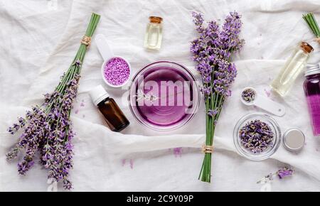 Lavendelöle, Flüssigkeiten, Rauchgase, Lavendelblüten auf weißem Stoff. Set skincare Spa Beauty Kosmetik-Produkte. Ätherisches Lavendelöl. Apotheke Stockfoto