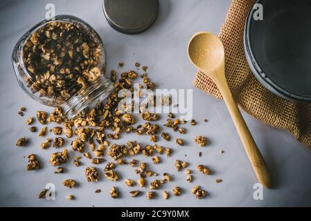 Hausgemachte gesunde und nahrhafte Paleo Diät Frühstück Müsli in Glas mit Holzlöffel und blaue Keramikschale auf Marmor Küchentisch Stockfoto
