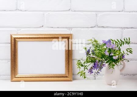 Gold verzierte Landschaft, Rahmen Mockup mit lila Vogel vetch Blumen in der Krug Vase. Leerer Rahmen für Präsentationsgrafiken. Vorlage Fra Stockfoto