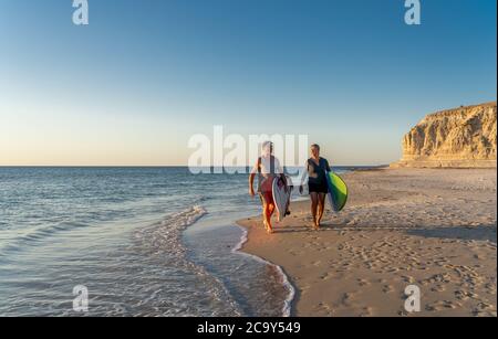 Reifes Paar mit Surfbrettern am schönen Strand, das Paradies und aktiven Lebensstil genießen. Attraktiv fit Mann und Frau Surfen und Spaß haben. In Trave Stockfoto