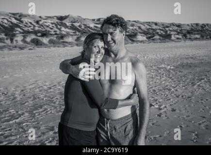 Im Freien Porträt von glücklich reifen Paar in der Liebe auf leeren abgelegenen Strand. Mann und Frau genießen zusammen Outdoor-Lifestyle auf dem Mantel. Aktive reale pe Stockfoto