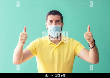 Portrait von glücklichen reifen Mann mit Schutzmaske lächelnd mit Daumen nach oben was Sicherheit und Prävention für Coronavirus Ausbreitung während covid-19 Stockfoto