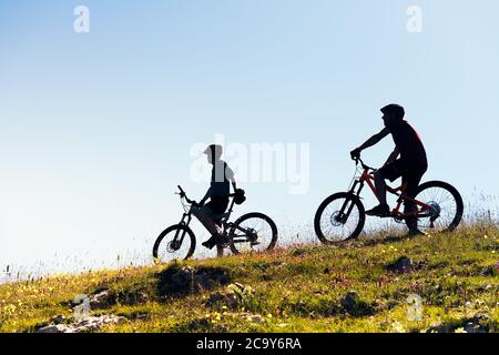Silhouette von zwei jungen Männern auf dem Land mit ihren Mountainbikes, Konzept des Sports mit Freunden und gesunden Lebensstil in der Natur, kopieren Raum fo Stockfoto