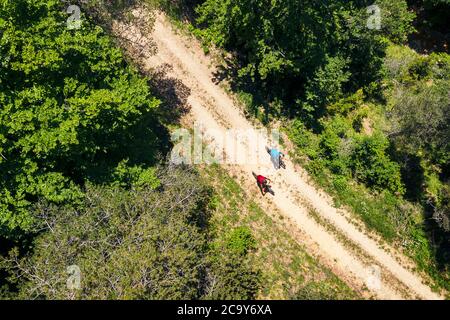 Blick von oben auf ein paar Radfahrer, die ihre Mountainbikes entlang einer unbefestigten Straße auf dem Land fahren, Konzept des Sports mit Freunden und gesunder Lebensstil Stockfoto