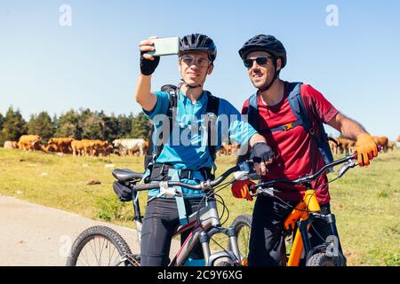 Zwei junge Radfahrer, die ein Selfie mit dem Telefon während ihrer Mountainbike-Route, Konzept des Sports mit Freunden und gesunden Lebensstil in der Natur, Cop Stockfoto