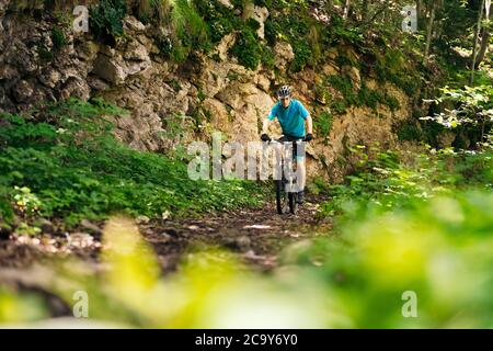 Vorderansicht eines Radfahrers, der sein Mountainbike auf einem Waldweg fährt, Konzept von Sport und gesunder Lebensweise in der Natur Stockfoto