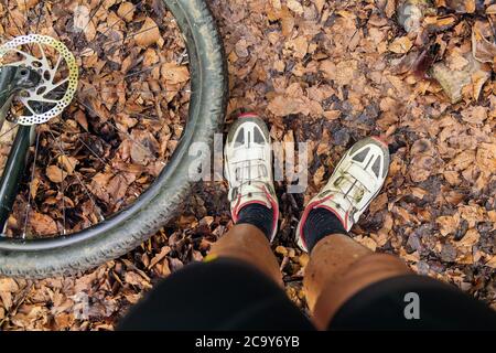 Detail eines Radfahrers schmutzige Beine und das Rad seines Mountainbikes, Konzept der Anstrengung im Sport und gesunder Lebensstil in der Natur, Copy Space for Text Stockfoto