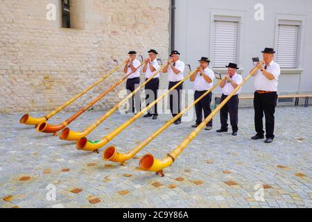 Schweizer Alphornspieler geben am Schweizer Nationalfeiertag ein Konzert vor der Abteikirche Notre-Dame in Payerne, Kanton Waadt, Schweiz. Stockfoto