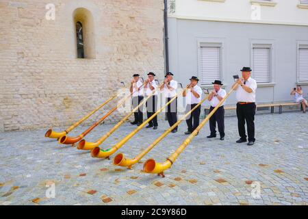 Schweizer Alphornspieler geben am Schweizer Nationalfeiertag ein Konzert vor der Abteikirche Notre-Dame in Payerne, Kanton Waadt, Schweiz. Stockfoto