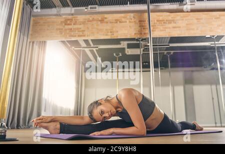 Schöne junge Frau Stretching in Pole Dance Studio Stockfoto