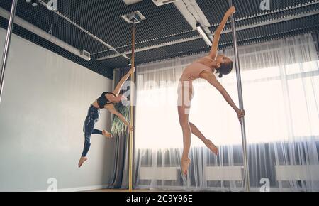 Zwei schöne junge Frauen, die Pole-Dance-Tricks Stockfoto