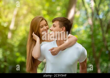 Romantisches Millennial-Paar, das sich liebevoll im Sommerpark ansieht Stockfoto