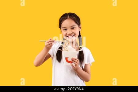 Asiatische Mädchen Essen Nudeln Aus Box Mit Essstäbchen, Studio Shot Stockfoto