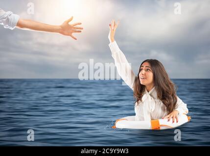 Geschäftsfrau im Meer mit Rettungsgurt erhält Hilfe Stockfoto