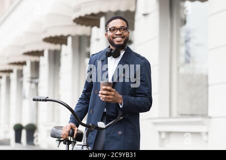 Schöner afro Geschäftsmann hält Kaffee und sein Fahrrad Stockfoto