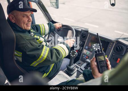 Lächelnder, gutaussehender Fahrer hört seinen Kollegen zu Stockfoto
