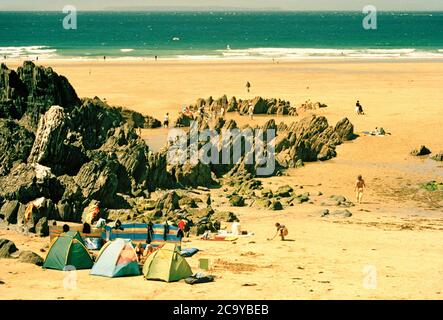 Urlauber und ihre Windbreaks auf Combesgate Beach, North Devon, Großbritannien Stockfoto