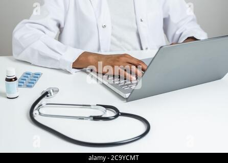 Hände einer afro Ärztin mit einem Laptop Stockfoto