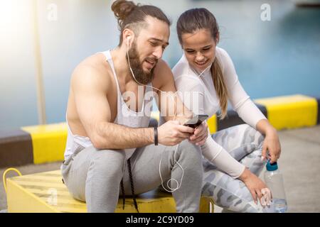 Lächelnd sportliche Dame und den jungen Athleten Mann verbringen Tag aktiv zusammen und genießen melden Sie Workout und schöne Seascape draußen und jetzt entspannen Stockfoto