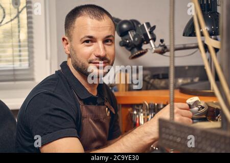 Ruhiger dunkelhaariger Handwerker, der in seinem Atelier sitzt Stockfoto