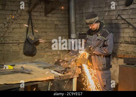 Professionelle schmied Sägen von Metall mit der Kreissäge in der Schmiede, Werkstatt. Handarbeit, Handwerk und Schmiedekunst Konzept Stockfoto