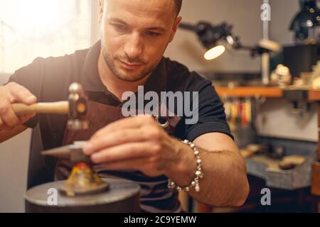 Serious Metallschmied Behandlung eines Werkstücks auf dem Amboss platziert Stockfoto