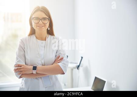 Schöne glückliche Kosmetologin posiert bei der Fotokamera in ihrem Büroraum Stockfoto