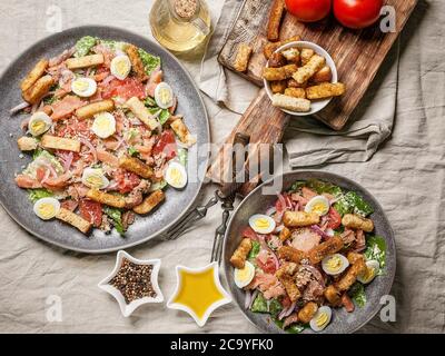 Zwei Portionen Caesar-Salat mit rotem Fisch, Romaine-Salat, Wachteleiern und Knoblauchcroutons Stockfoto