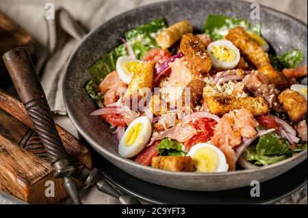 Nahaufnahme des Caesar Salats mit rotem Fisch, Romaine-Salat, Wachteleiern und Knoblauchcroutons. Stockfoto