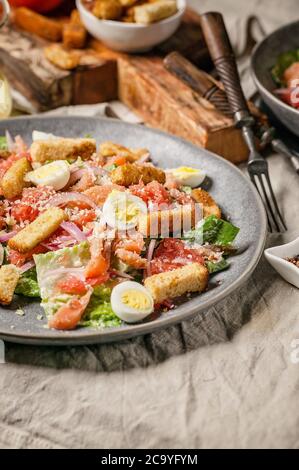 Nahaufnahme Caesar Salat mit gesalzenem Lachs, Rosensalat, Wachteleiern, Knoblauchcroutons. Vertikale Aufnahme Stockfoto