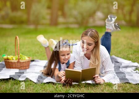 Mutter Und Kleine Tochter Mit Picknick Buch Gemeinsam Im Freien Stockfoto