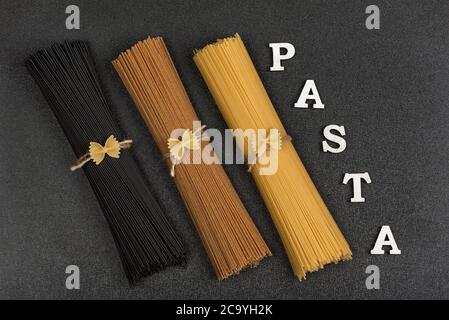 Verschiedene Arten von italienischen Pasta auf grauem Hintergrund und Wort Pasta. Lebensmittel Hintergrund. Stockfoto